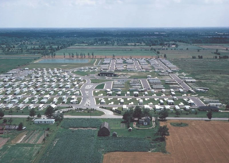 Aerial photograph of manufactured-home rows, internal streets and adjacent farmland.
