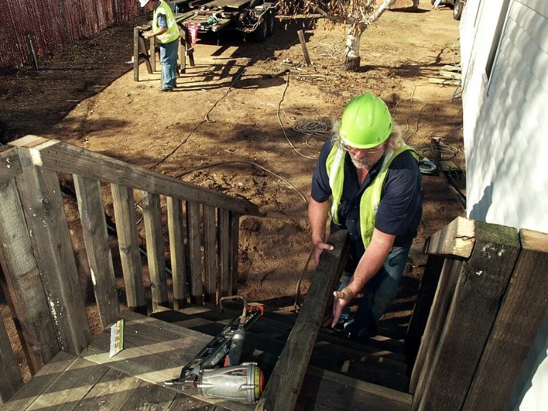 A worker constructing wooden steps beside a mobile home.
