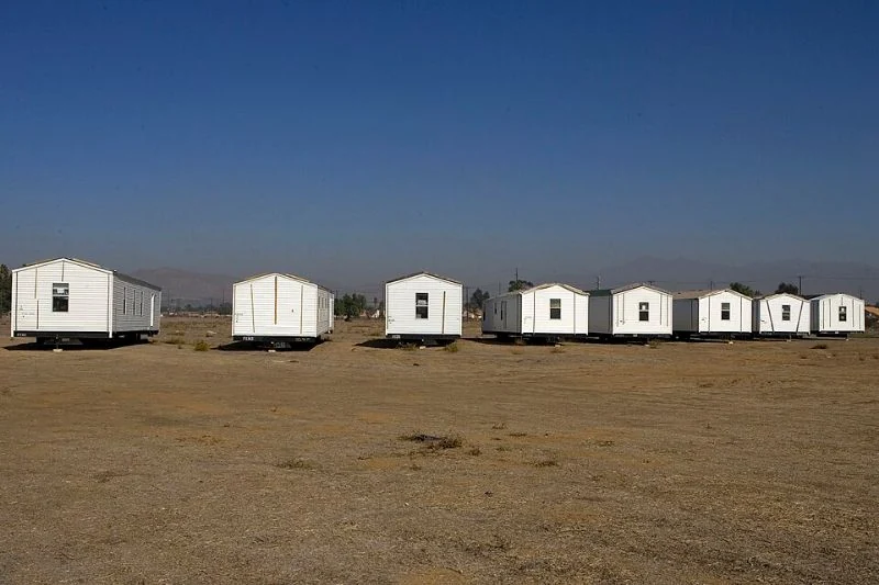 Several mobile homes standing separately across an open dirt staging area.